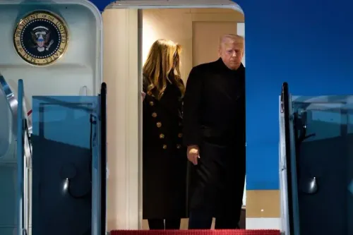 رجل يرتدي سترة داكنة ينزل من الطائرة الرئاسية الأمريكية، يرافقه شخص آخر، مع شعار الرئاسة خلفهم.