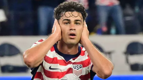 لاعب الوسط الأمريكي جيو رينا يرتدي قميص منتخب الولايات المتحدة بتعبير وجه يعكس التركيز خلال مباراة دولية، مع انتقاله الجديد إلى نادي Strasbourg الفرنسي.