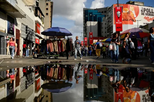 مشهد مزدحم في مركز تسوق بكراكاس، حيث يتجول المتسوقون بين المحلات، مع وجود طابور أمام متجر للملابس الداخلية بسبب التخفيضات.