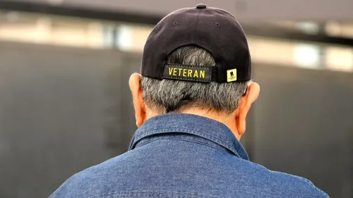 رجل مسن يرتدي قبعة مكتوب عليها "محارب قديم" من الخلف، يعكس تجارب المحاربين القدامى في الحكومة الأمريكية وتأثير قرارات الإدارة الحالية.