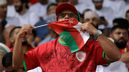 مشجع عماني يرفع علم بلاده بفخر خلال مباريات خليجي 27 وسط أجواء حماسية تعكس تأهل منتخب عمان لنصف النهائي بعد قرعة حاسمة.