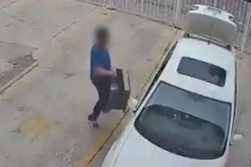 رجل يرتدي قميصًا أزرق يحمل حقيبة ثقيلة بالقرب من سيارة بيضاء، بينما يُظهر الفيديو جزءًا من التحقيق في مقتل لورينا موراليس.