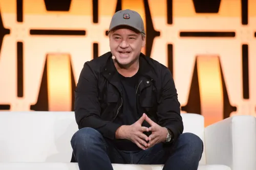 تظهر الصورة فينس زامبيلا، مبتكر ألعاب الفيديو، يتحدث خلال حدث، مع خلفية مضيئة تعكس تأثيره في صناعة الألعاب.