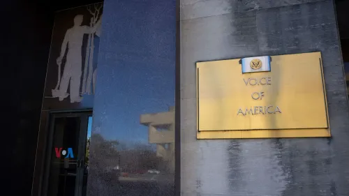 مبنى إذاعة صوت أمريكا يظهر لافتة ذهبية تحمل الاسم، مع تصميم فني على الجدار يرمز للعمل والإعلام.