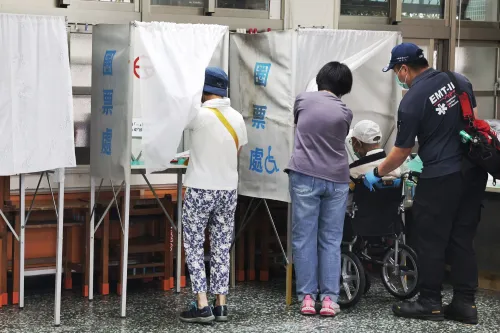 ناخبون في تايوان داخل مراكز الاقتراع خلال انتخابات سحب الثقة، مع وجود مسعف يساعد شخصًا مسنًا على كرسي متحرك.