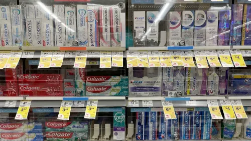 رف من معجون الأسنان ومزيل العرق في متجر مغلق خلف زجاج، مع علامات أسعار واضحة، يعكس تحديات السلاسل التجارية في منع السرقة وتلبية احتياجات المتسوقين.