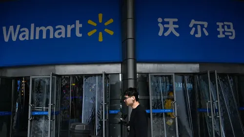 واجهة متجر وول مارت مع زبون يسير بجانب الأبواب الزجاجية، تعكس تأثيرات الحرب التجارية بين الولايات المتحدة والصين على سلاسل التوريد.
