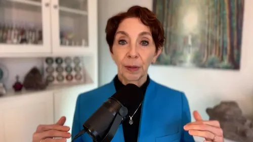 امرأة تتحدث في ميكروفون، ترتدي سترة زرقاء، في خلفية تحتوي على زجاجات وأعمال فنية، تناقش القلق والإبداع كوسيلة للتغلب عليه.