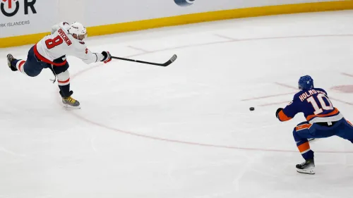 ألكسندر أوفيتشكين، لاعب واشنطن كابيتالز، يسدد الكرة في مباراة هوكي، مع لاعب منافس يتجه نحوها، وسط أجواء حماسية.