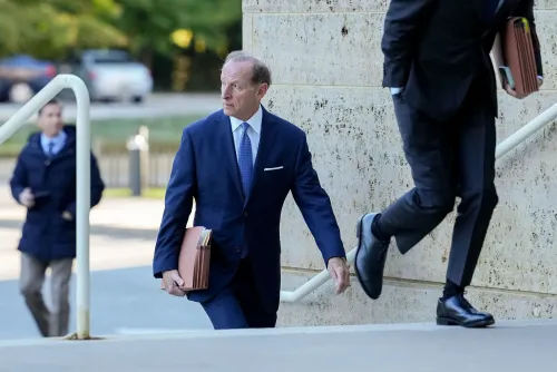 المحامي آبي لويل يدخل المحكمة حاملاً ملفات قانونية، بينما يظهر شخص آخر يصعد الدرج، في سياق قضايا قانونية بارزة.