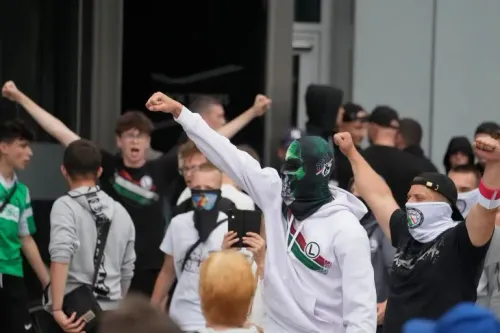 مجموعة من المتظاهرين في تورون، بولندا، يرفعون قبضاتهم أثناء مسيرة مناهضة للهجرة، مع لافتات تدعو لوقف الهجرة غير الشرعية.