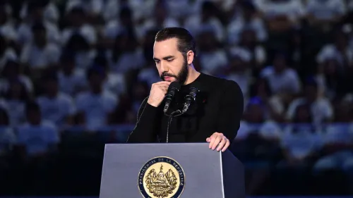 ناييب بوكيلي يتحدث في حدث رسمي، مع وجود شعار الحكومة خلفه، وسط جمهور كبير يرتدي ملابس بيضاء.