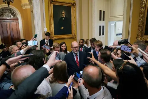 ازدحام إعلامي حول زعيم الأقلية في مجلس الشيوخ تشاك شومر خلال اجتماع لمناقشة تمويل الحكومة، مع وجود لوحة تاريخية خلفه.