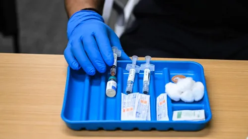 أدوات طبية تشمل حقن لقاح الحصبة وزجاجات دواء، موضوعة على صينية زرقاء، تشير إلى جهود مكافحة تفشي المرض في تكساس ونيو مكسيكو.