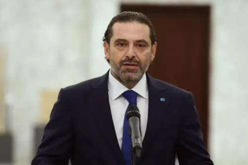سعد الحريري يتحدث في مؤتمر صحفي، مرتديًا بدلة رسمية، مع خلفية من الجدران البيضاء، في سياق السياسة اللبنانية وتحدياتها.