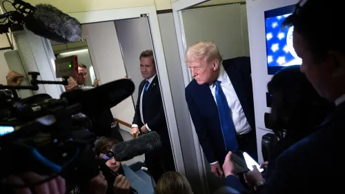دونالد ترامب يتحدث مع الصحفيين في طائرة، محاطًا بكاميرات وصحفيين، في سياق الجدل حول الترحيل والأزمة الدستورية.