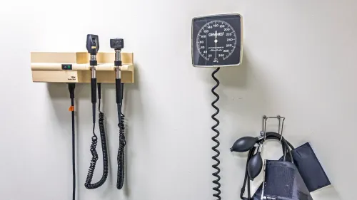 أدوات طبية مثبتة على الحائط تشمل جهاز قياس ضغط الدم ومصباح فحص، تعكس أهمية الرعاية الصحية وبرنامج Medicaid للأمريكيين ذوي الدخل المنخفض.