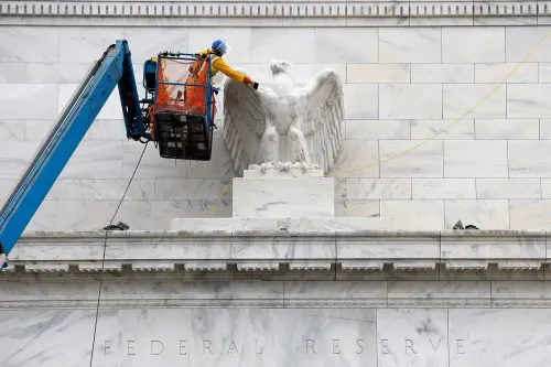 عمال يقومون بأعمال صيانة على تمثال النسر فوق مدخل مبنى الاحتياطي الفيدرالي، في سياق تغييرات السياسة النقدية.
