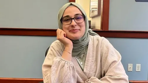 روميسا أوزتورك، طالبة دكتوراه في جامعة تافتس، مبتسمة أثناء حديثها، ترتدي حجابًا، في مكان داخلي هادئ.