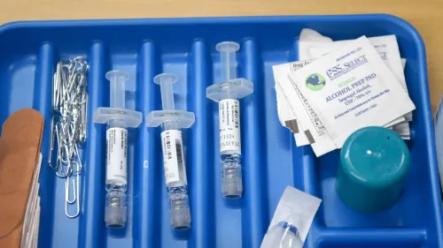 مجموعة من الحقن الطبية والأدوات المستخدمة في التطعيم، موضوعة على صينية زرقاء، مع مواد تحضيرية مثل الكحول والضمادات، تشير إلى أهمية اللقاحات.