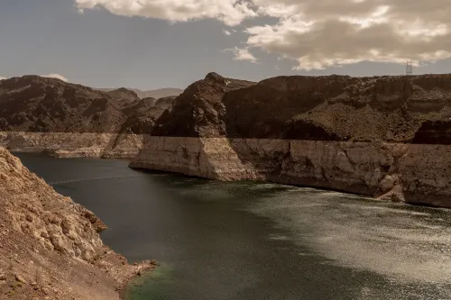 منظر طبيعي يظهر بحيرة ذات مستوى مياه منخفض، محاطة بتضاريس صخرية جافة، مما يعكس تأثيرات الجفاف المتزايد بسبب تغير المناخ.