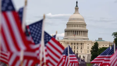 مبنى الكابيتول الأمريكي يظهر في الخلفية، مع أعلام الولايات المتحدة ترفرف في المقدمة، مما يرمز إلى النشاط السياسي والتشريعي.