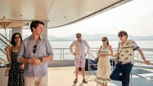 مجموعة من الشخصيات الرئيسية من مسلسل "اللوتس الأبيض" يتفاعلون على متن يخت، مع خلفية بحرية جميلة، حيث تبرز الأجواء الصيفية.