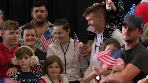 مجموعة من اللاجئين الجنوبيين الأفريقيين البيض تحتفل بوصولهم إلى الولايات المتحدة، حاملي أعلام أمريكية، في مطار واشنطن دالاس.