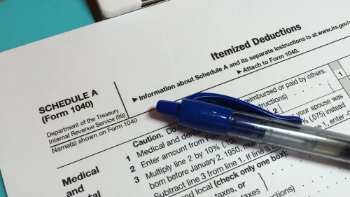 نموذج ضريبي يحمل عنوان "الخصومات المفصلة" مع قلم أزرق، يوضح تفاصيل الخصومات الضريبية الفيدرالية.