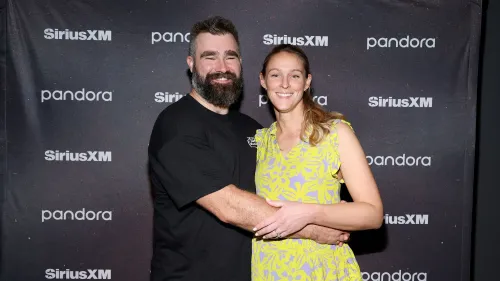 جيسون وكايلي كيلسي يحتفلان بوصول ابنتهما الرابعة، فينلي. يظهر الزوجان مبتسمين في حدث، مع خلفية تحمل شعار "SiriusXM".