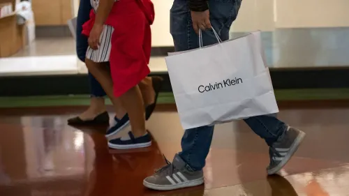 شخص يحمل حقيبة تسوق تحمل علامة "كالفن كلاين" بينما يسير في مركز تسوق، مما يعكس تأثير العلامة التجارية في السوق الصينية.