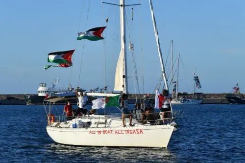 قارب يحمل أعلام فلسطين والجزائر، مع نشطاء على متنه، يبحر في المياه، تعبيرًا عن دعمهم لجهود كسر الحصار على غزة.