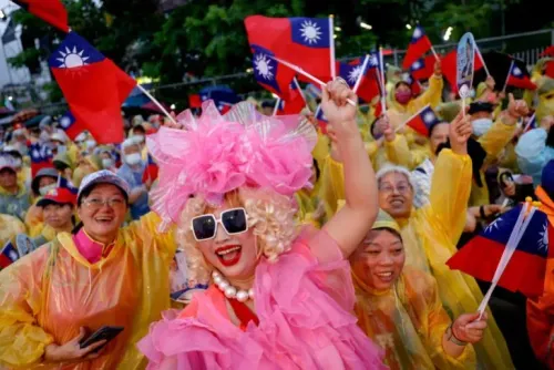 محتجون يرتدون ملابس ملونة ويحملون أعلام تايوانية خلال تجمع حاشد، مع التركيز على شخصية ترتدي زيًا مميزًا وملونًا.