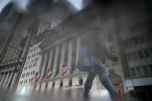 واجهة مبنى البورصة الأمريكية في نيويورك، مع شخص يحمل حقيبة، تعكس القلق الاقتصادي في ظل تباين الثروات.