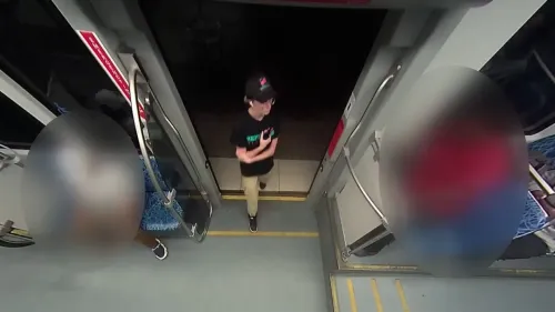 شابة ترتدي قميص مطعم بيتزا وسماعات أذن، تجلس في قطار خفيف، بينما يظهر رجل يرتدي قميصًا أحمر يقترب منها.