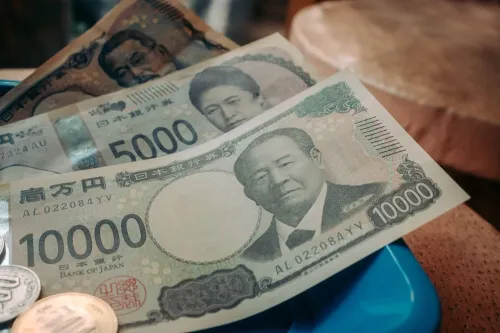 عملات يابانية ورقية بفئات 10000 و5000 ين مع عملات معدنية، تعكس تقلبات سوق السندات والين وتأثيرها على الاقتصاد العالمي.