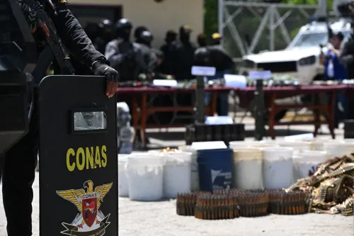 عناصر من قوة الأمن تعرض أسلحة وذخائر مصادرة أثناء حملة ضد عصابات المخدرات، مع التركيز على جهود مكافحة الجريمة في أمريكا اللاتينية.