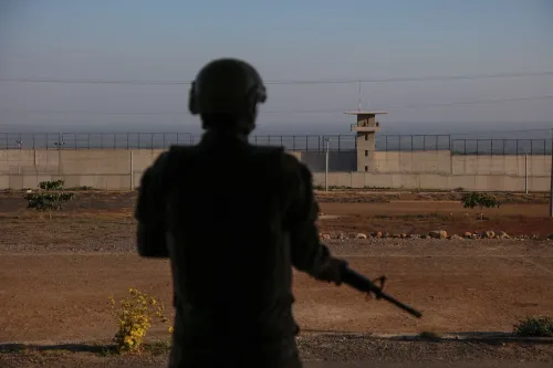 مشهد لجندي مسلح يقف أمام سجن محاط بسياج، يعكس الظروف القاسية في السجون التي تعزز من قوة العصابات في أمريكا اللاتينية.