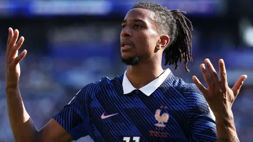 لاعب كرة القدم مايكل أوليس يرتدي قميص المنتخب الفرنسي خلال مباراة في كأس العالم 2026، معبراً عن تركيزه وأدائه المميز.