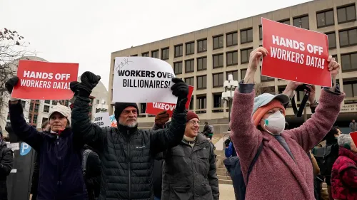 محتجون يحملون لافتات تطالب بحماية بيانات العمال، في تظاهرة ضد استحواذ الشركات على المعلومات الحكومية.