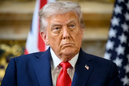 صورة للرئيس ترامب وهو ينظر بجدية، مع العلم الأمريكي خلفه، تعكس التوترات حول تهديداته لوسائل الإعلام المحلية.