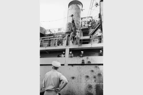 صورة تُظهر ضابطاً أمريكياً يتفقد الأضرار في السفينة USS Liberty بعد الهجوم الإسرائيلي عام 1967، مع وجود بحارة في الخلفية.