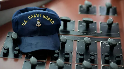 قبعة خفر السواحل الأمريكية موضوعة على لوحة تحكم، مما يعكس أهمية الأمن في القواعد البحرية في ظل اعتقال زوجة أحد أفراد الخدمة.