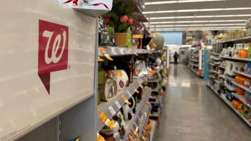 شعار Walgreens يظهر على رف في متجر، مع ممرات مليئة بالمنتجات، مما يعكس التحديات التي تواجهها الشركة في ظل التحولات المالية.