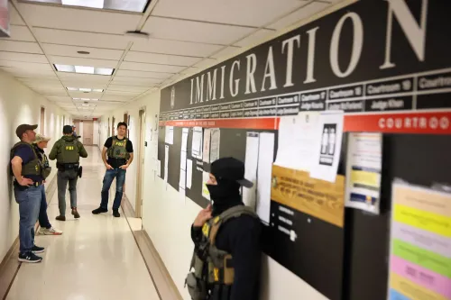 أفراد من إدارة الهجرة والجمارك في ممر مكتب الهجرة، مع لافتة تشير إلى قسم الهجرة، مما يعكس التوترات حول مشاركة بيانات Medicaid.