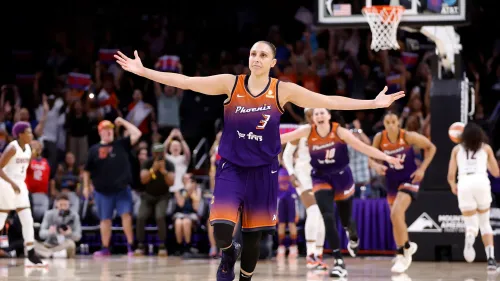 ديانا توراسي، لاعبة كرة السلة الشهيرة، تحتفل بعد تسجيل نقطة مهمة، بينما يشجعها الجمهور في مباراة لفريق فينيكس ميركوري.