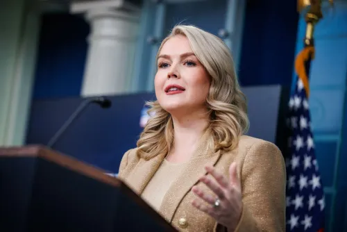 امرأة تتحدث في مؤتمر صحفي، ترتدي سترة ذهبية، مع العلم الأمريكي خلفها. تتعلق القضية بإفراجها بكفالة بعد اعتقالها من إدارة الهجرة.