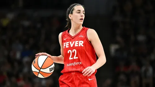 لاعبة كرة سلة ترتدي زي فريق "Fever" الأحمر، تحمل كرة سلة وتظهر في لحظة تركيز خلال مباراة.