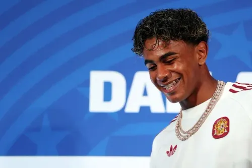 لامين يمال لاعب منتخب إسبانيا لكرة القدم يبتسم أثناء مؤتمر صحفي قبل نصف نهائي كأس العالم، مرتدياً قميص المنتخب وعقوداً ذهبية.