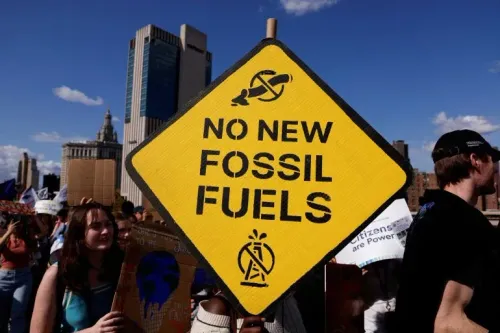 لا لوقود الأحفوري الجديد، لافتة صفراء تحمل رسالة قوية ضد مشاريع الطاقة الأحفورية، مع حشد من المتظاهرين في الخلفية.